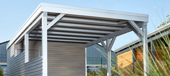 Carport mit Holzdach als Unterstand für ein geparktes Auto.