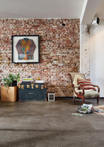 Loft-Wohnraum mit Ziegelwand und dunklem Designboden.